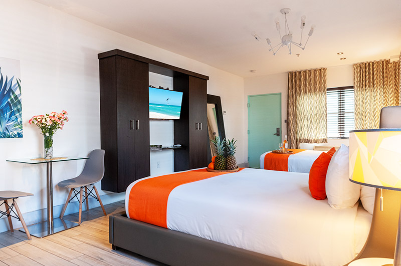 A hotel room with a double bed, wardrobe, TV, desk, and chair.
